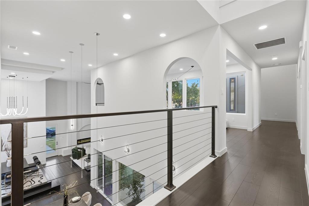 Upper-level hallway featuring dark wood-finish flooring, recessed lighting, and a contemporary cable railing system