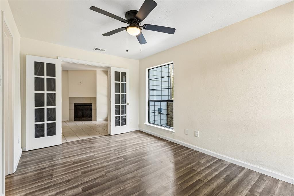 Interior room featuring wood-finish flooring, a window with grid detailing, and a ceiling fan with integrated lighting