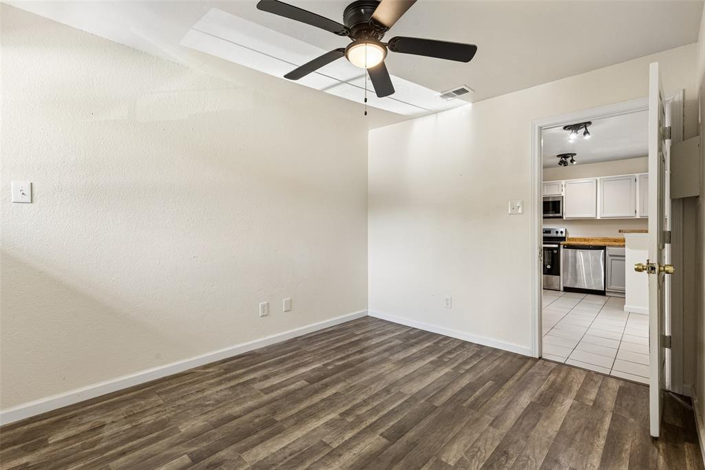 Room featuring wood-finish flooring, a ceiling fan, and white walls
