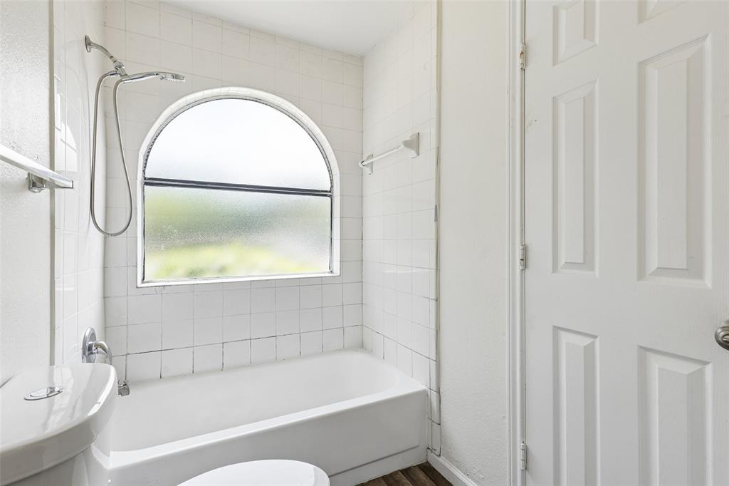 Bathroom featuring a tiled shower/tub combination with an arched privacy window