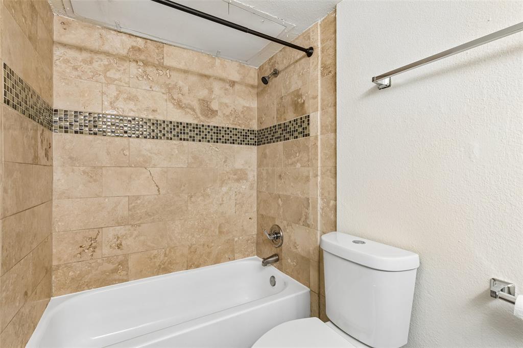 Bathtub with stone-finish tile surround and decorative mosaic accent band
