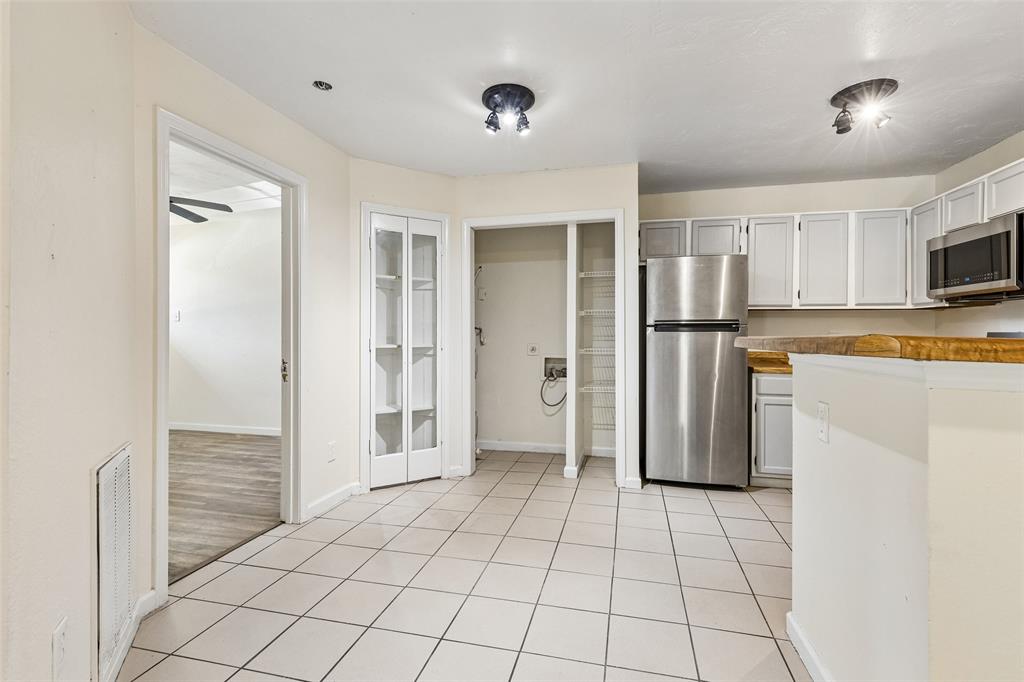 Kitchen area featuring light-toned tile flooring, light-toned cabinetry, and stainless steel appliances