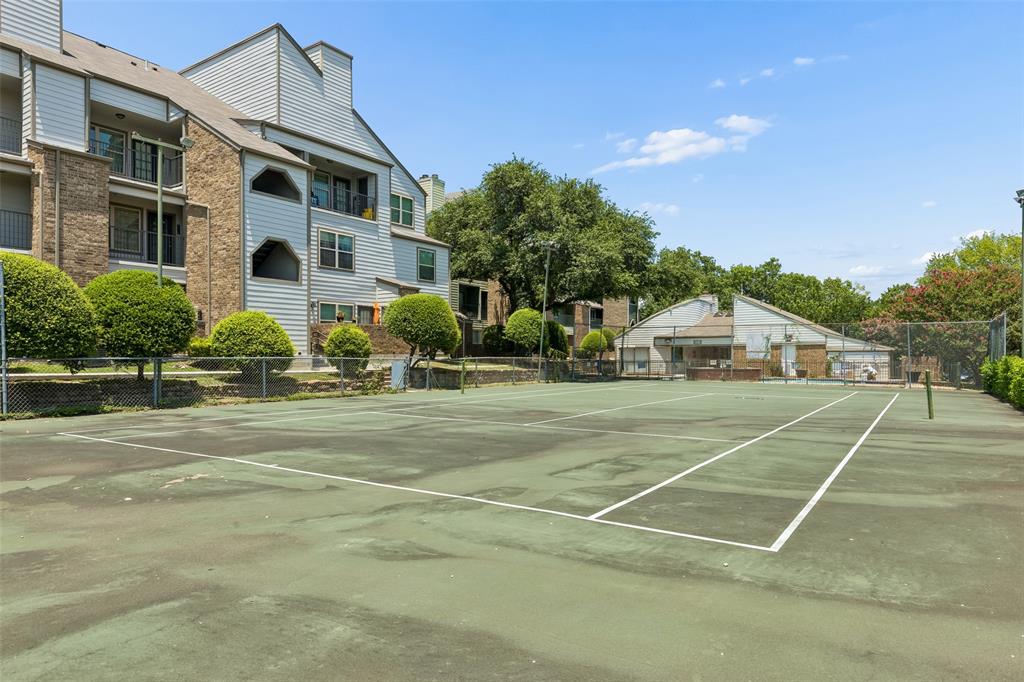 Outdoor tennis court with perimeter fencing, surrounded by mature trees and landscaping Outdoor tennis court with perimeter fencing, surrounded by mature trees and landscaping