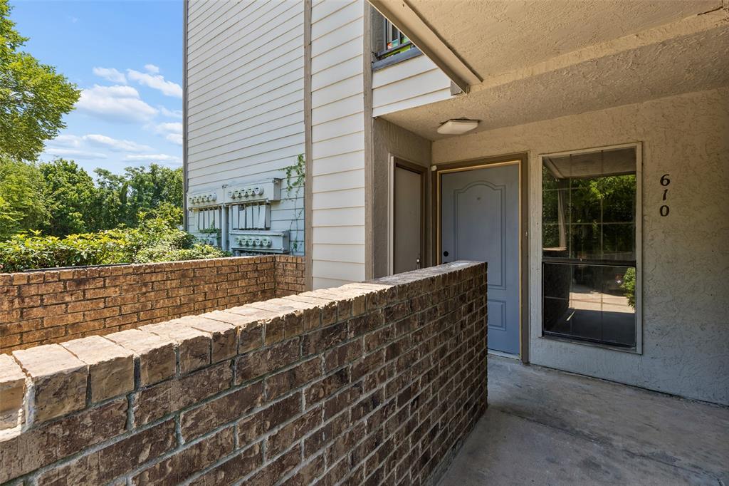 Brick privacy wall framing an entryway with a light-toned door, an adjacent window, and concrete flooring Brick privacy wall framing an entryway with a light-toned door, an adjacent window, and concrete flooring