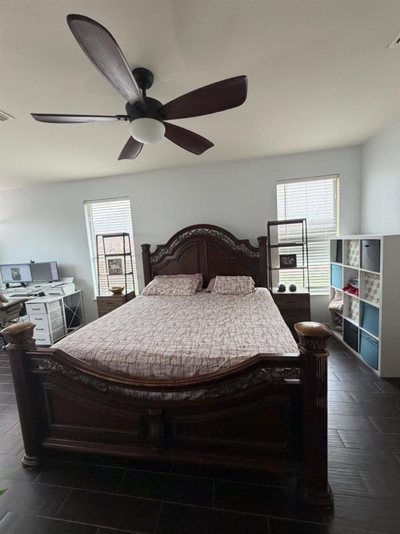 Spacious room featuring dark wood-finish flooring, two large windows with blinds, and white painted walls