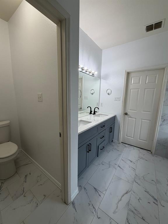 Modern bathroom featuring a dual vanity with a light gray cabinet, white countertop, and black fixtures