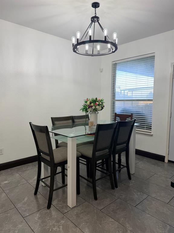 Dining area featuring a contemporary black wagon wheel chandelier, large format tile flooring, and a window with blinds