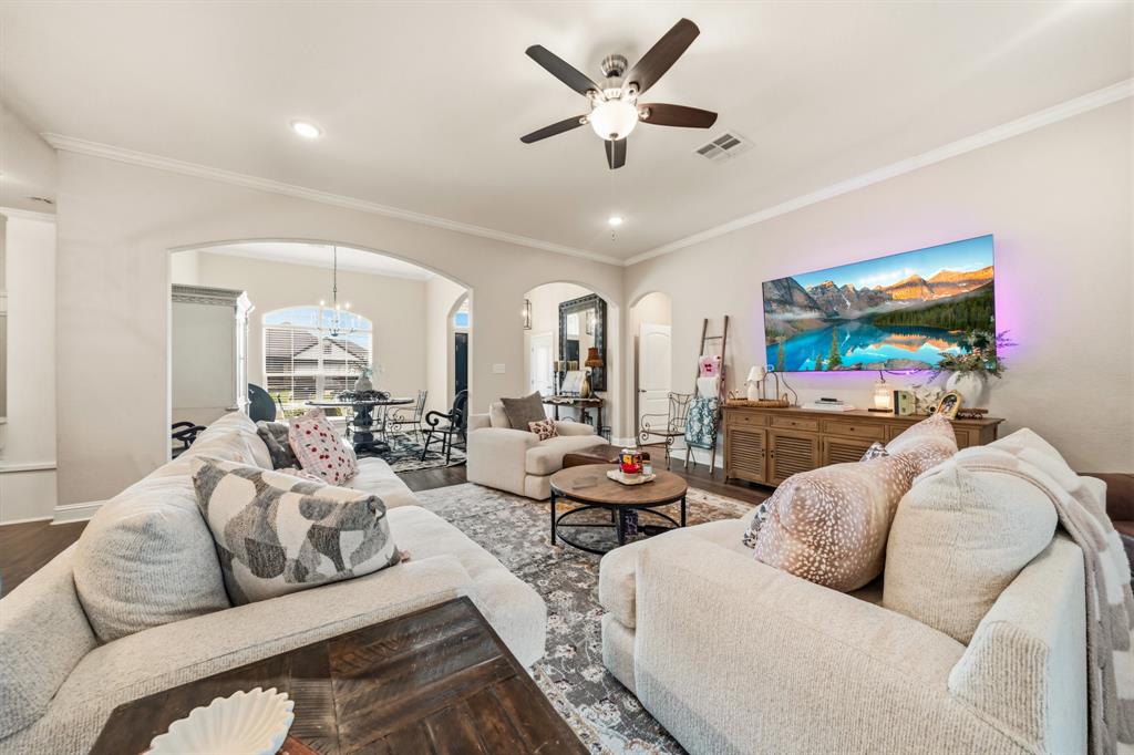 Spacious living area featuring wood-finish flooring, light neutral wall tones, and crown molding