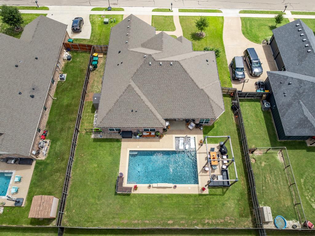 Spacious fenced backyard featuring a rectangular swimming pool with surrounding patio, a covered outdoor living area, and expansive green lawn