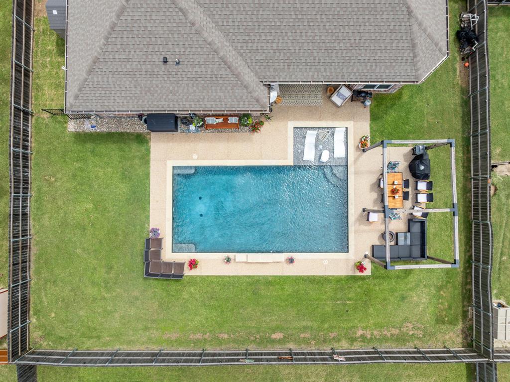 Private backyard oasis featuring a rectangular swimming pool with integrated sun shelf