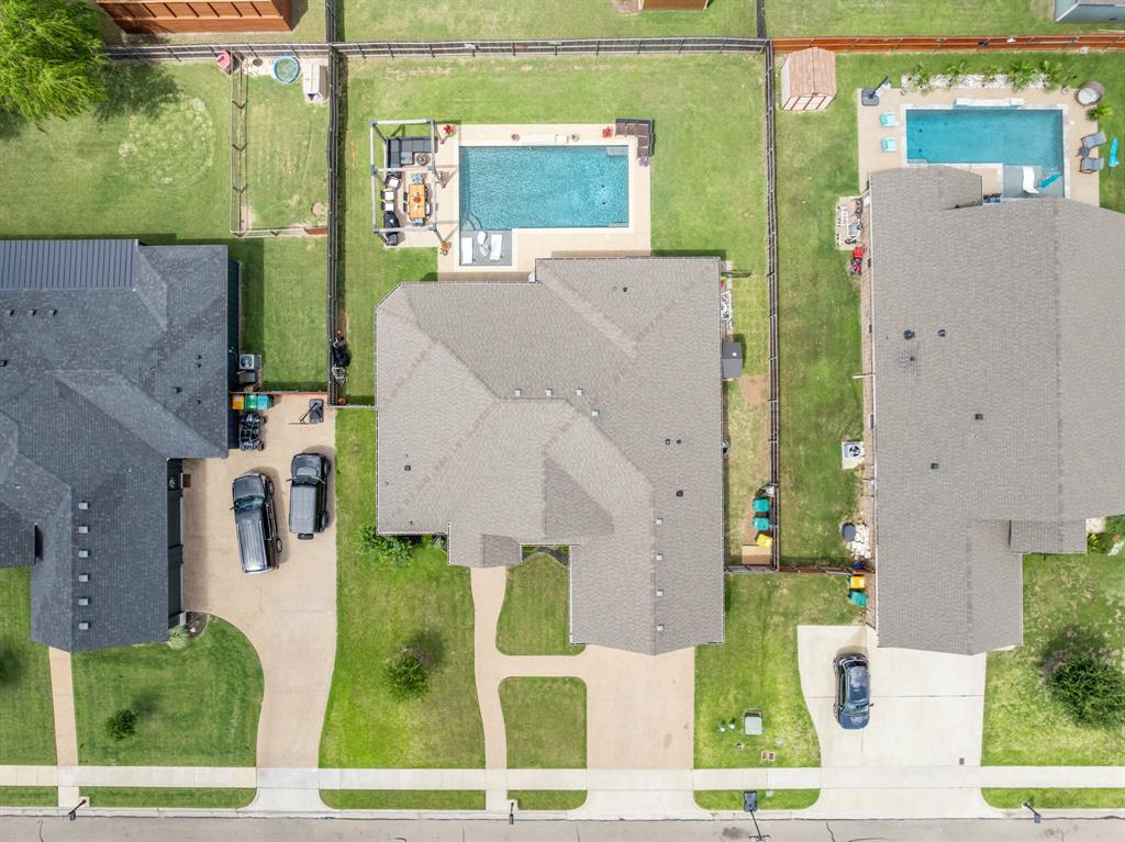 Expansive property featuring a rectangular pool with surrounding concrete decking, a substantial main residence with an asphalt shingle roof, and a paved driveway