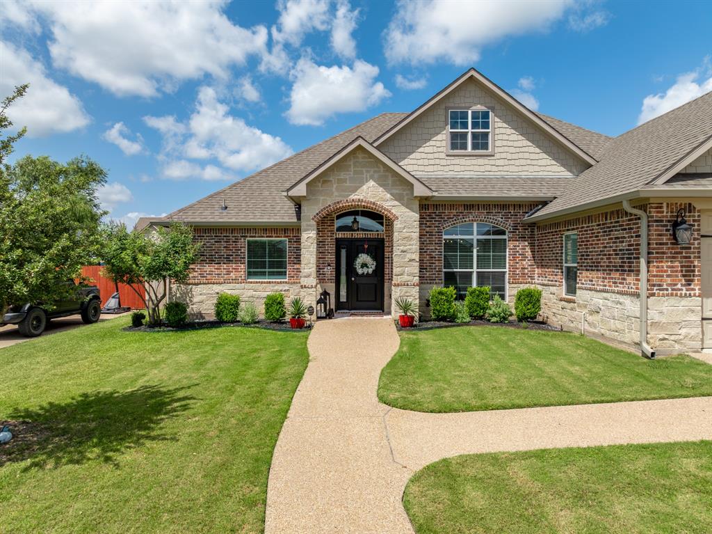 Traditional-style residence featuring a combination brick and stone facade, an arched entry, and a gabled roofline