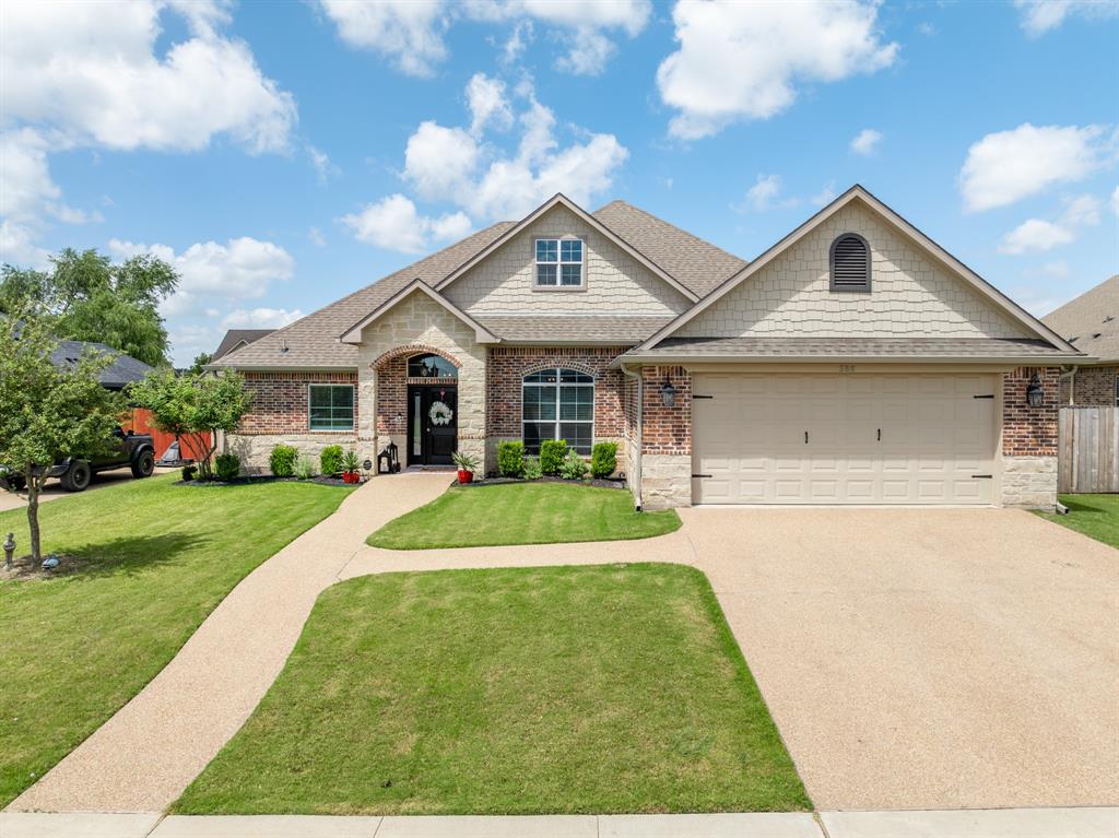 Brick and stone facade featuring a gable roofline and a two-car garage