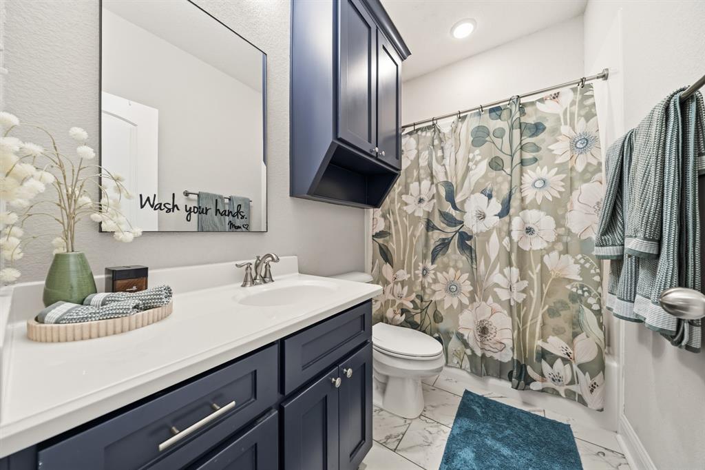 Bathroom featuring a vanity with dark blue cabinetry, a white countertop, and a rectangular mirror