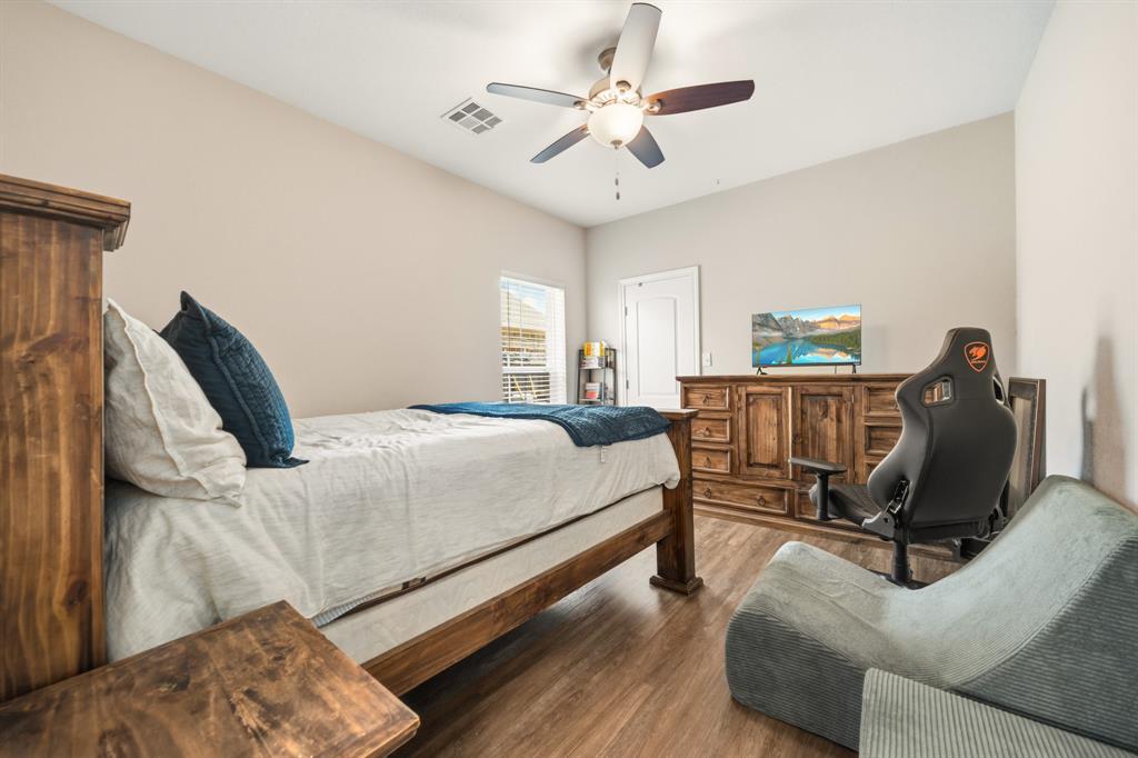 Bedroom featuring wood-finish flooring, a vaulted ceiling, a ceiling fan with integrated lighting, and a window with horizontal blinds