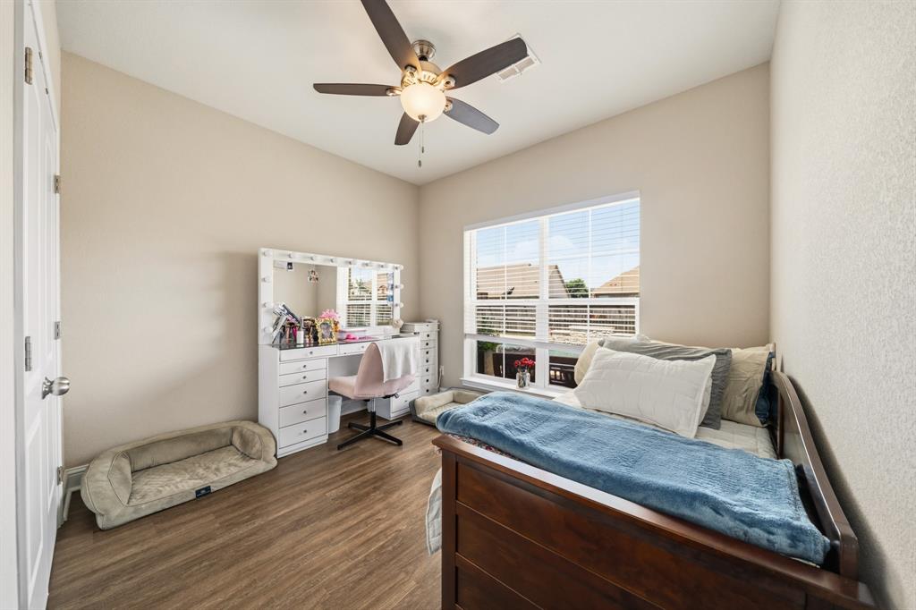 Bright interior room featuring wood-finish flooring, a large window with blinds, and a ceiling fan with integrated lighting