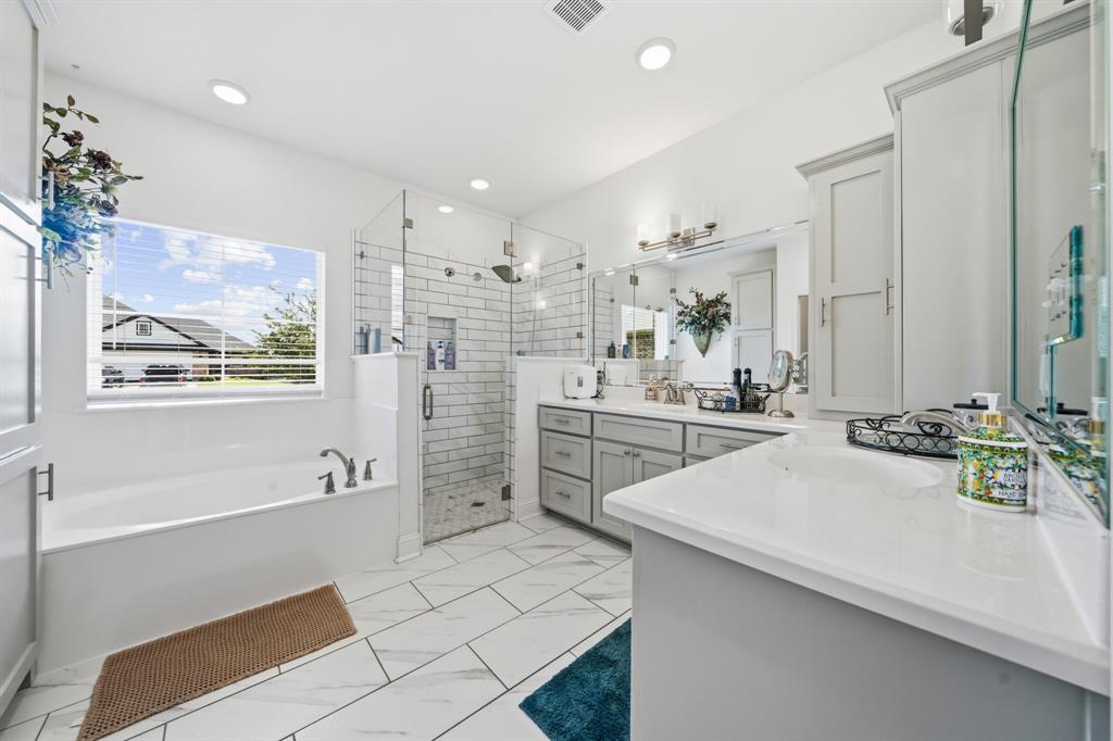 Bathroom featuring a built-in bathtub, a walk-in shower with subway tile, a dual vanity with light gray cabinetry and white countertops, and white tile flooring