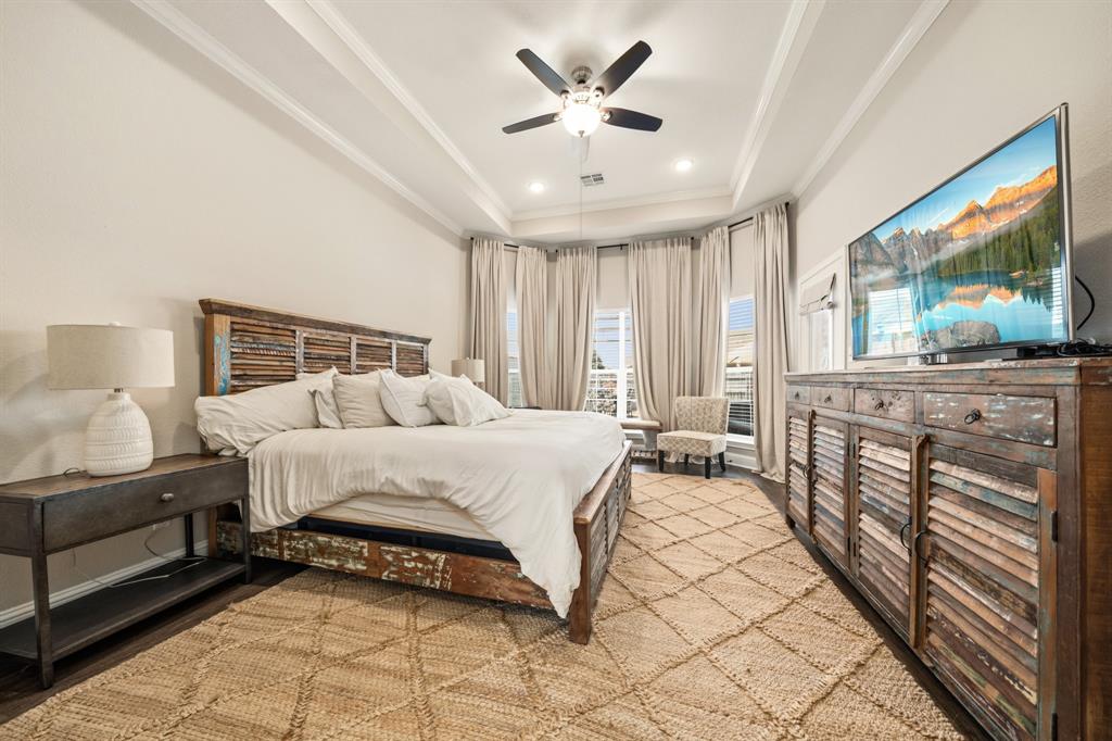 Spacious room with tray ceiling, dark wood-finish flooring, recessed lighting, and a ceiling fan