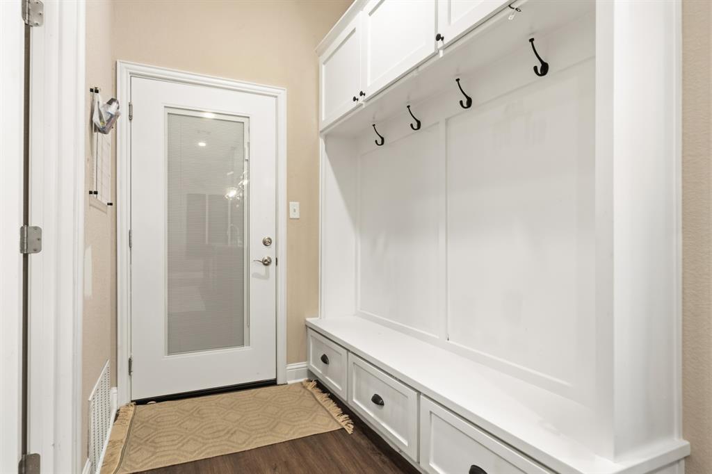 Built-in white cabinetry with a bench and storage drawers, featuring black hooks and hardware