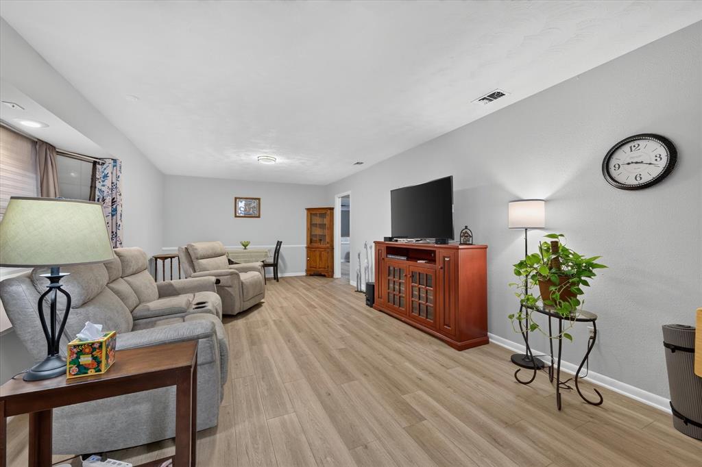 Spacious room with wood-finish flooring, light grey wall paint, recessed lighting, and white baseboards Spacious room with wood-finish flooring, light grey wall paint, recessed lighting, and white baseboards