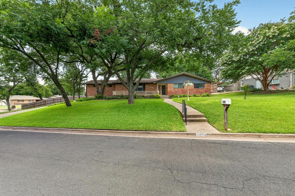 Brick and siding home featuring a front lawn with mature trees and a concrete walkway Brick and siding home featuring a front lawn with mature trees and a concrete walkway