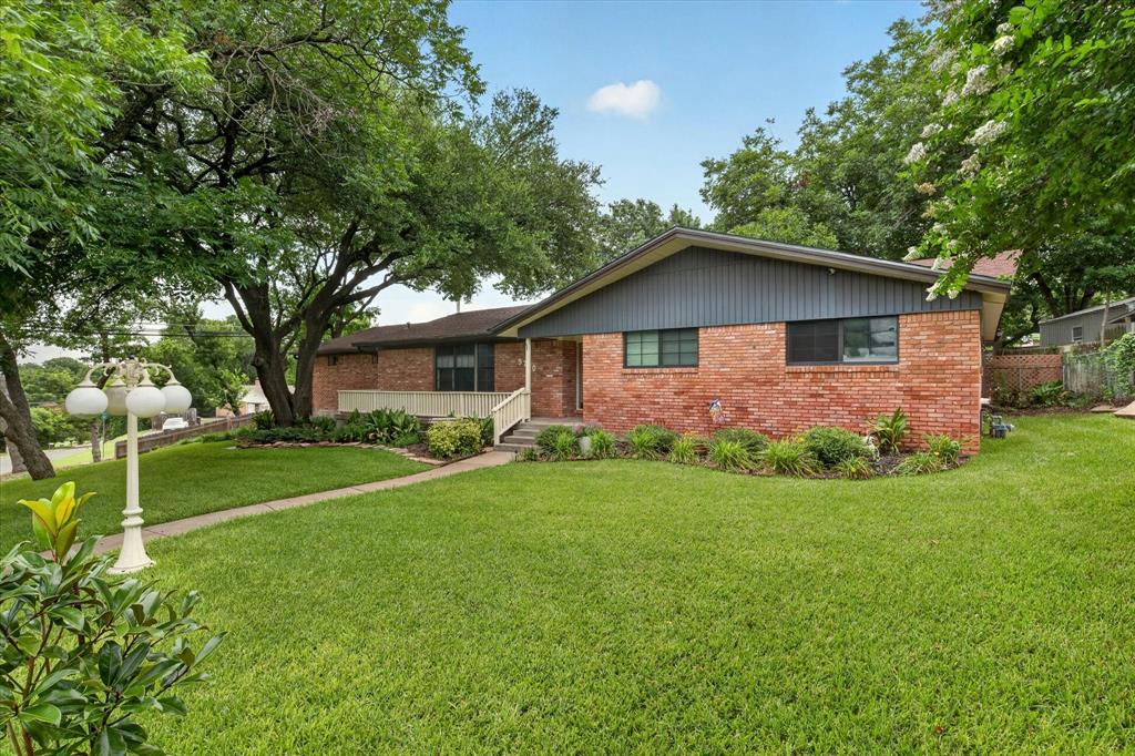 Brick-clad residence featuring a gabled roofline and dark siding accents Brick-clad residence featuring a gabled roofline and dark siding accents