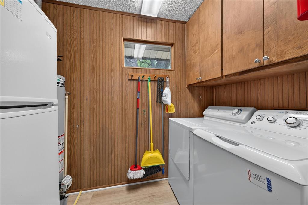 Utility room featuring wood-finish wall paneling, light wood-finish flooring, and upper cabinetry