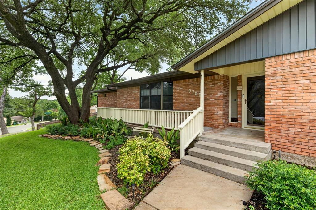 Brick exterior with dark gray vertical siding accents, concrete walkway, and stone-edged landscaping Brick exterior with dark gray vertical siding accents, concrete walkway, and stone-edged landscaping