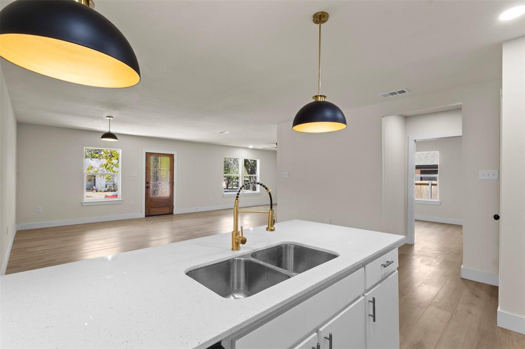 Kitchen island with a double basin stainless steel sink, gold-finish faucet, and white quartz countertop