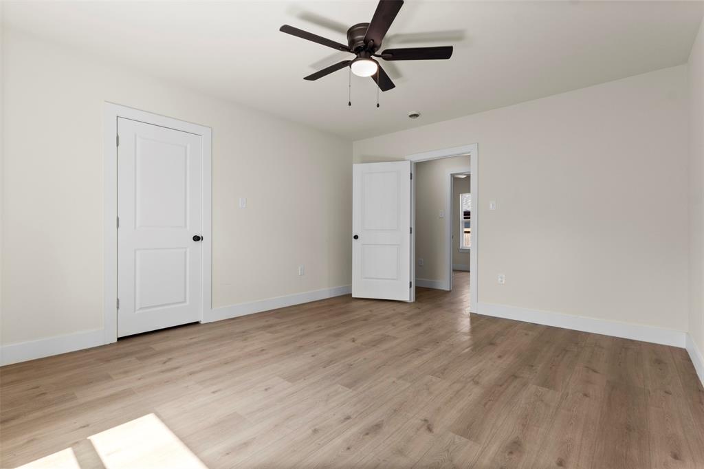 Wood-finish flooring, white trim, and a ceiling fan with light fixture