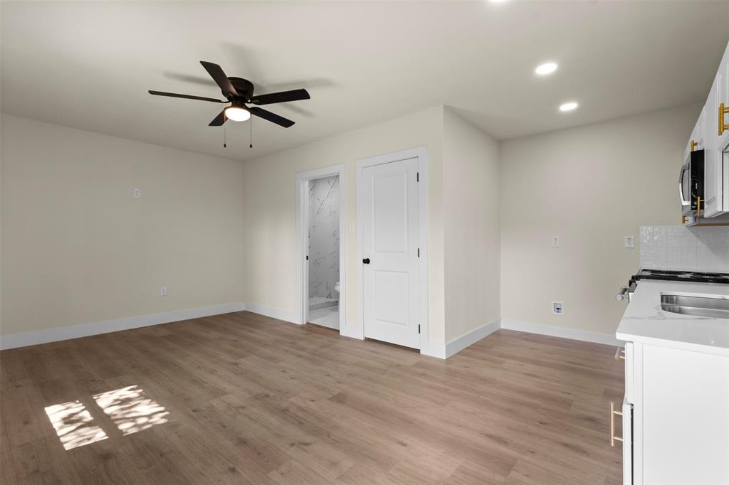 Light wood-finish flooring with a ceiling fan, recessed lighting, and a white flat-panel door