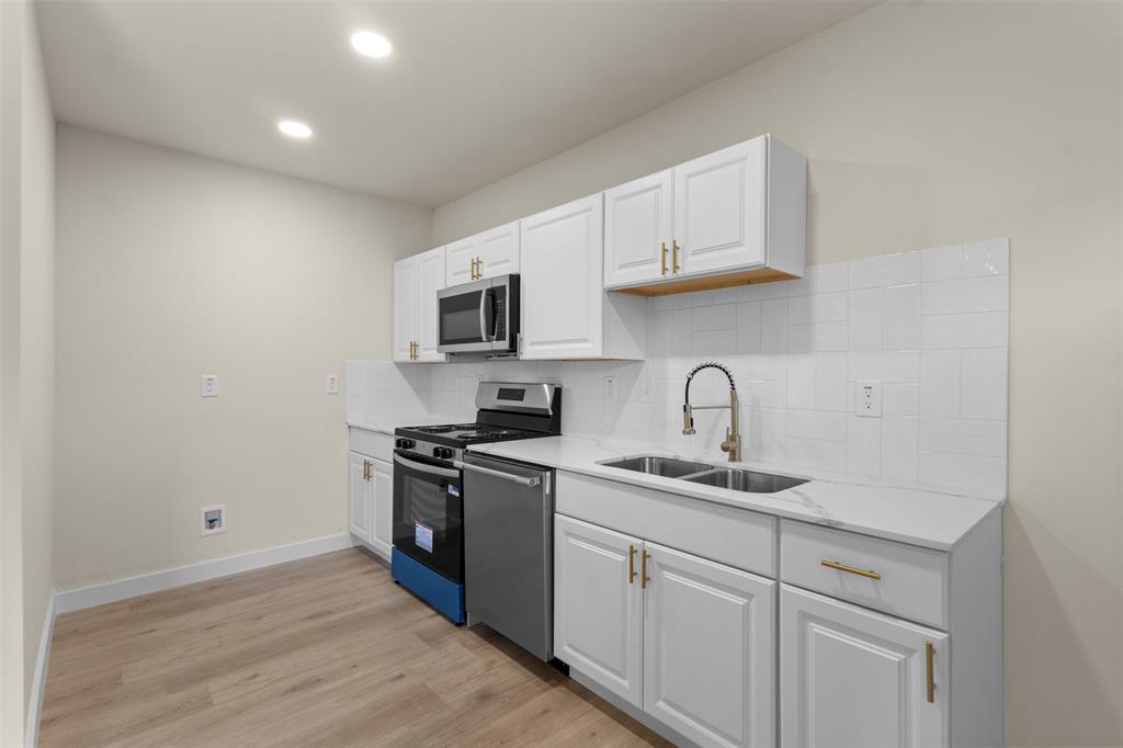 Kitchen featuring white cabinetry, stainless steel appliances, wood-finish flooring, and recessed lighting