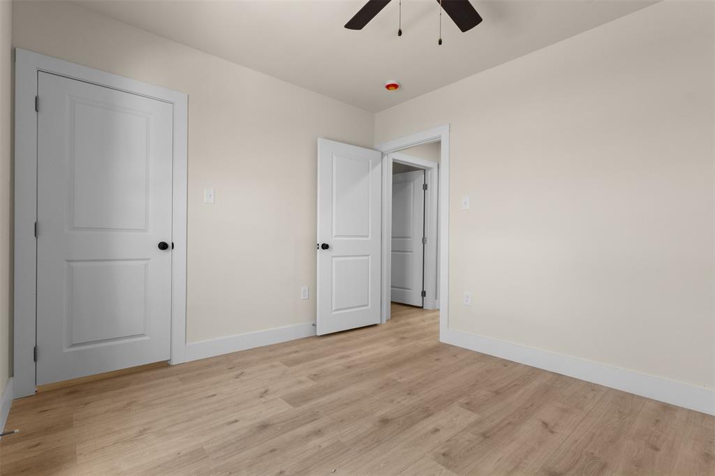 Light wood-finish flooring, neutral wall paint, white trim, and a ceiling fan