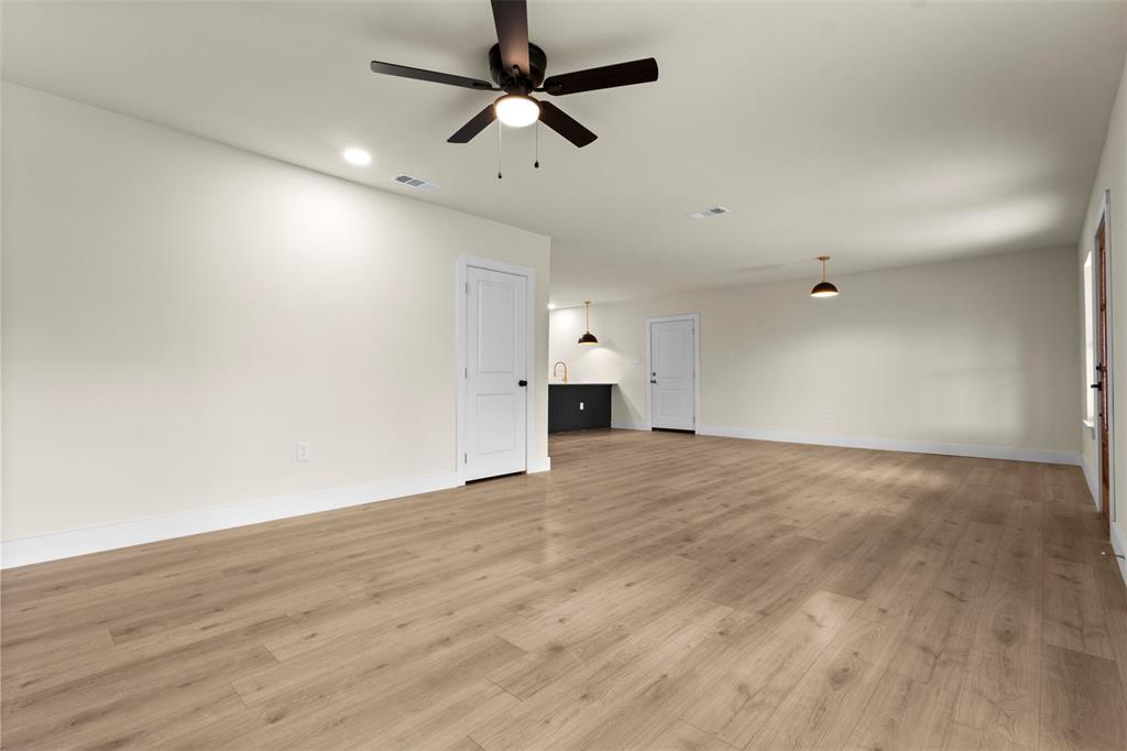 Spacious room featuring wood-finish flooring, recessed lighting, ceiling fan, and pendant lighting