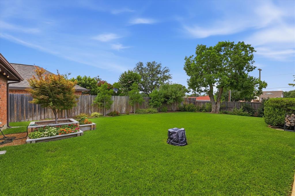 Large backyard with landscaped beds and a place for the outdoor firepit.  That is not a tree stump.
