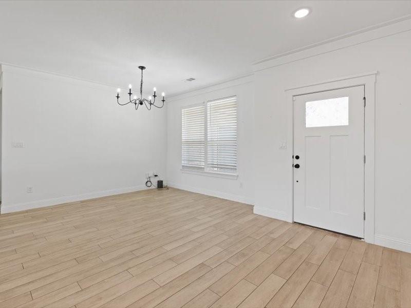 Bright living area featuring wood-finish flooring, white walls, and crown molding