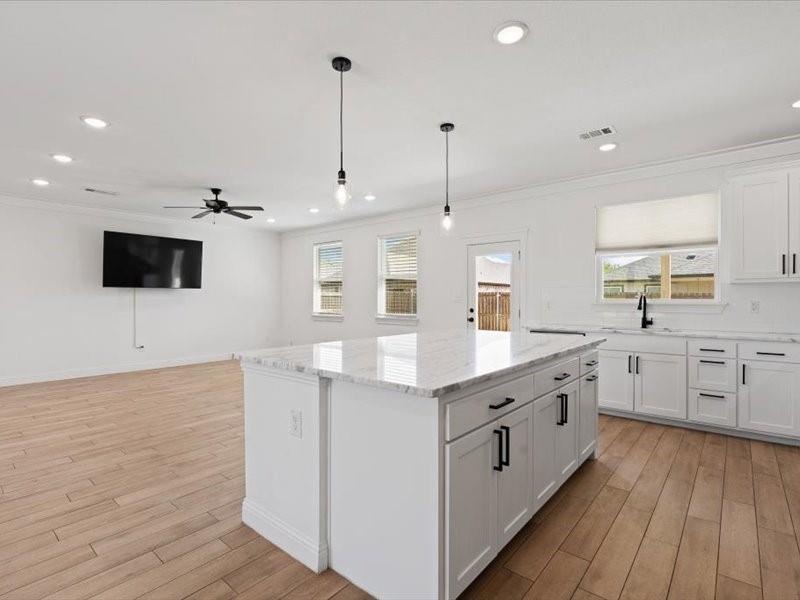Modern kitchen island featuring a white countertop, two pendant lights, and ample storage cabinetry Modern kitchen island featuring a white countertop, two pendant lights, and ample storage cabinetry