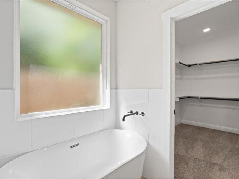 Freestanding soaking tub with matte black wall-mounted fixtures