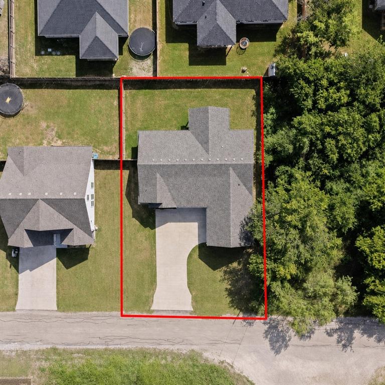 Aerial view showcasing a residential property with a gray shingle roof, a concrete driveway, and an expansive grass lawn