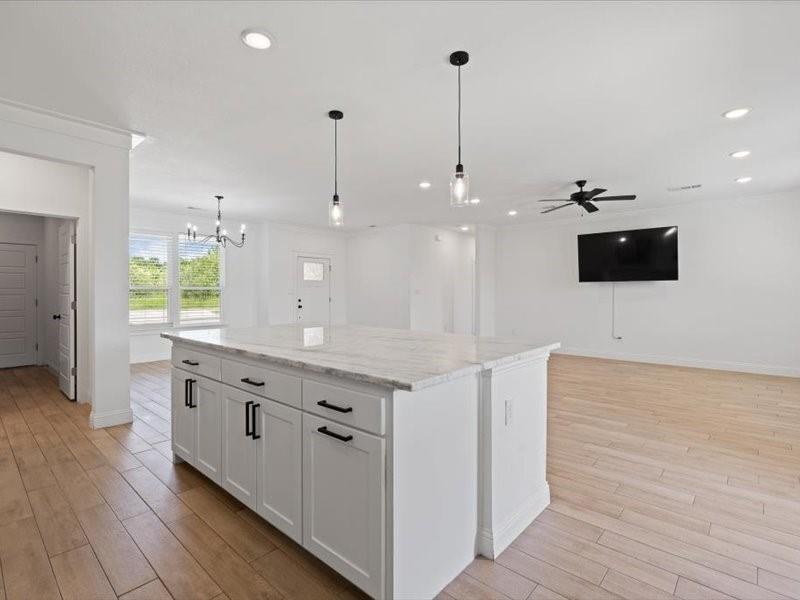 Kitchen island featuring white cabinetry, dark hardware, and a light-toned stone countertop Kitchen island featuring white cabinetry, dark hardware, and a light-toned stone countertop