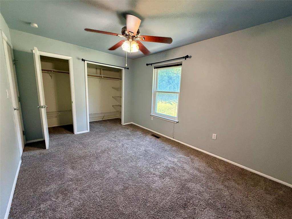 Primary Bedroom with two closets and beautiful view of green space. behind the condo.