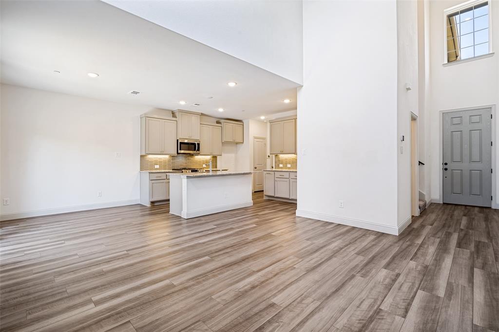 Open-concept living space featuring wood-finish flooring, a contemporary kitchen, and soaring ceilings