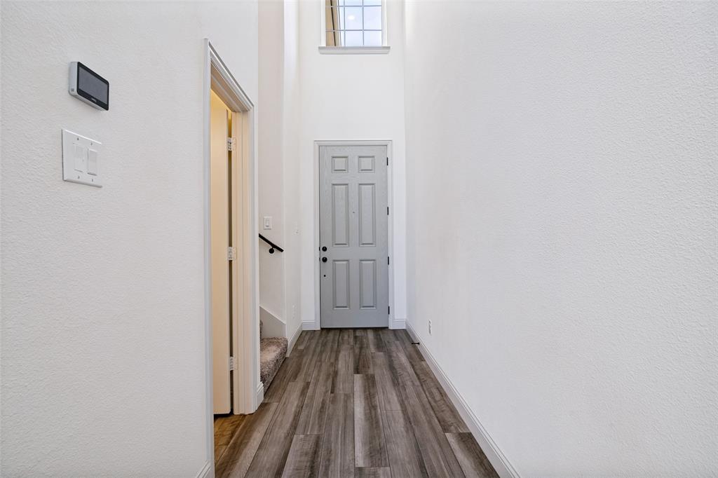 Foyer featuring high ceilings, wood-finish flooring, a light gray paneled door, and an upper window providing natural illumination