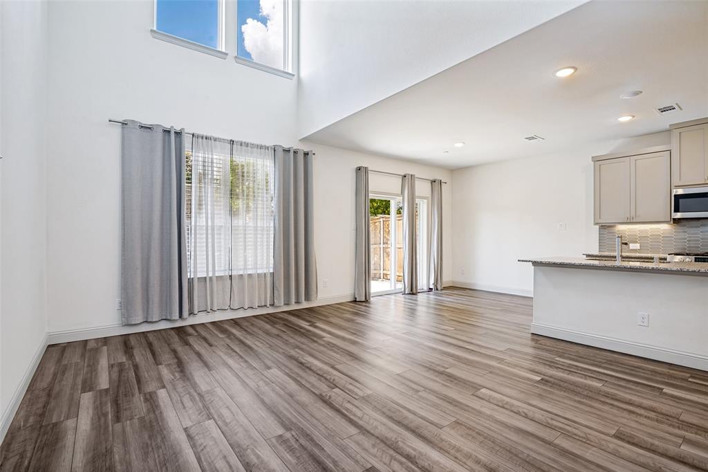 Expansive living area with high ceilings, wood-finish flooring, and upper transom windows
