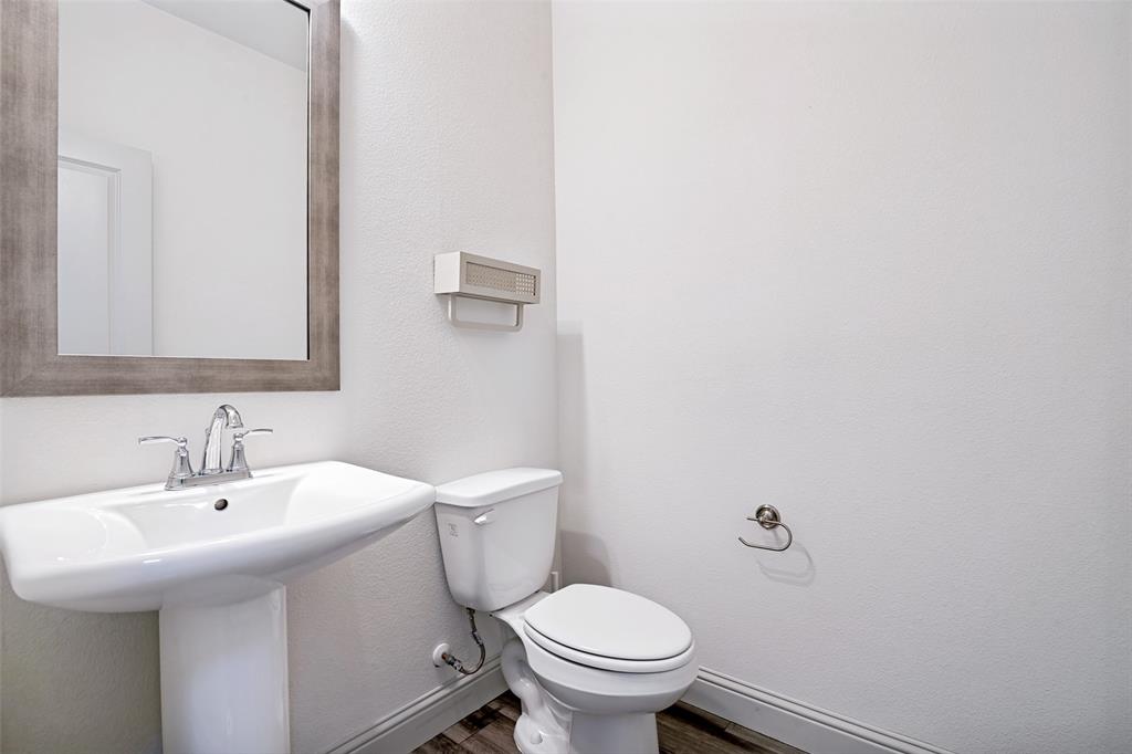Pedestal sink with chrome faucet, framed mirror, and wood-finish flooring