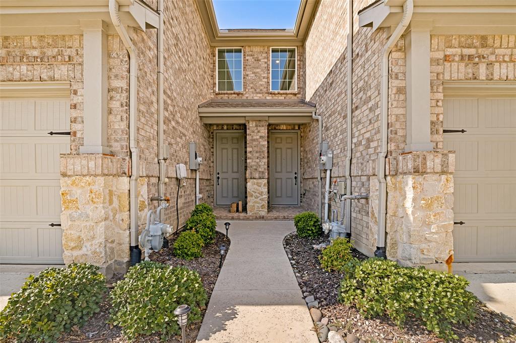 Brick exterior with stone accents, featuring two individual entry doors and two garage doors