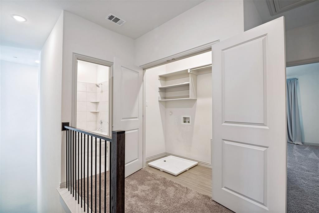 Upper-level hallway featuring a built-in laundry closet with shelving and utility hookups