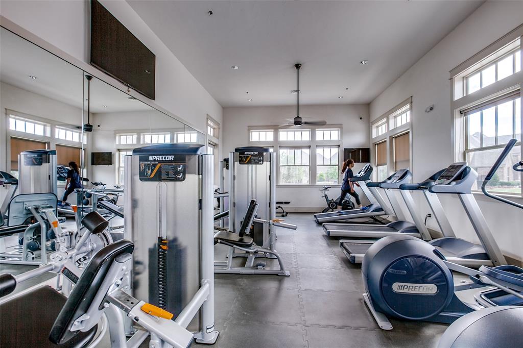 Fitness center featuring a mirrored wall, ample natural light from multiple windows, ceiling fan, and various exercise machines