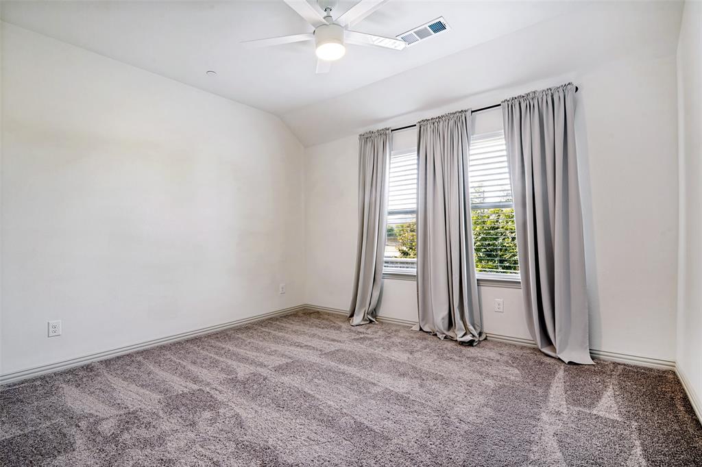 Spacious room featuring textured gray carpeting and white painted walls