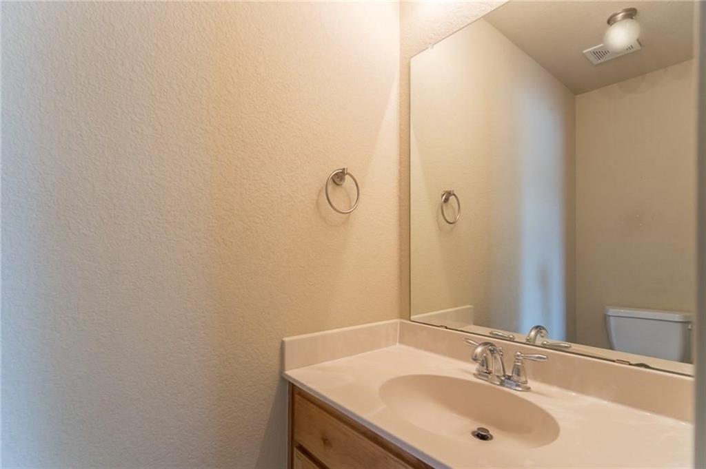 Bathroom vanity featuring a light-colored countertop with an integrated sink, chrome faucet, and a wood-finish cabinet